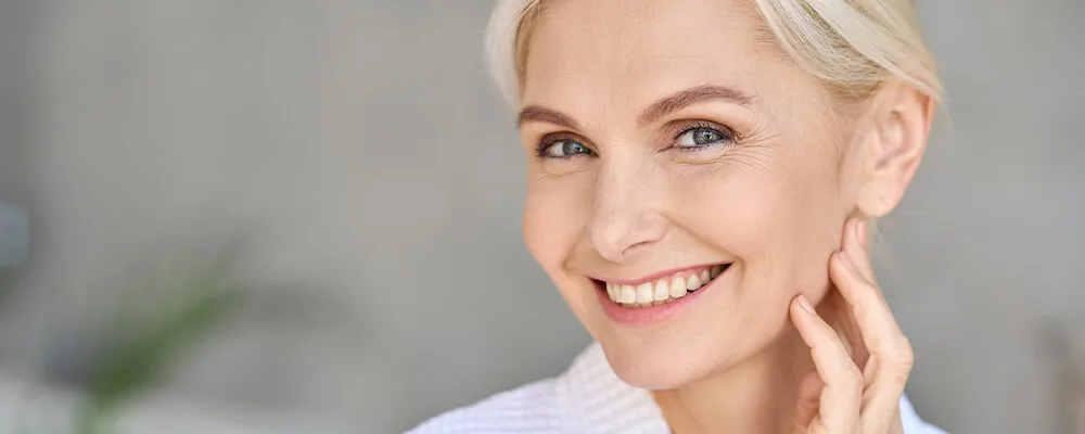 Lachende vrouw met een gladde, jeugdige huid, perfect voorbeeld van huidverjonging.
